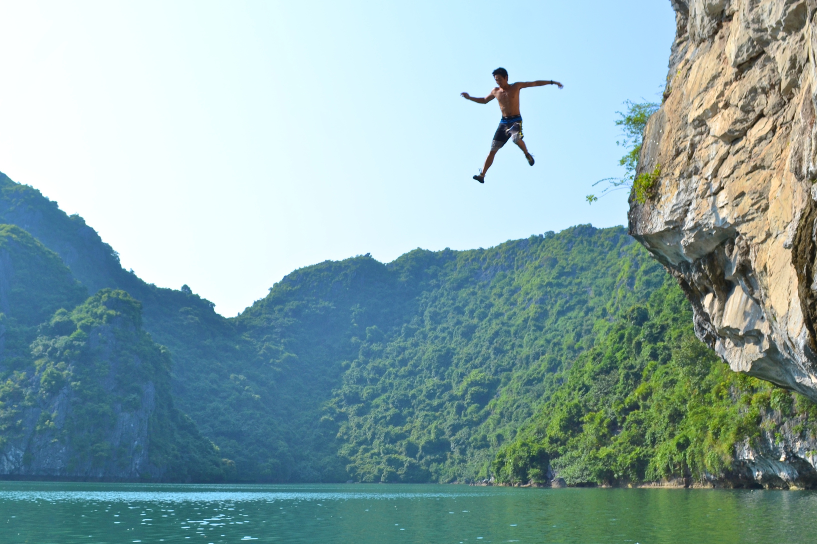 Cliff diver jumping from a high cliff into water demonstrating risk in extreme sports