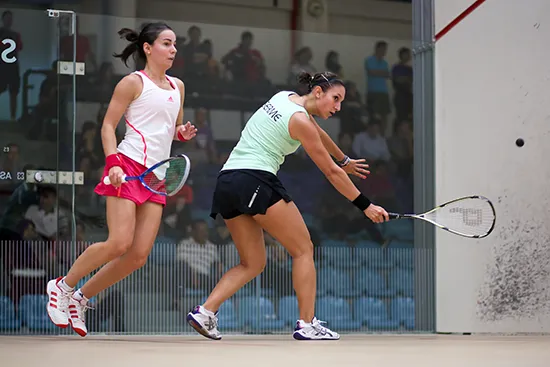 Two female squash players competing in an indoor match, illustrating amateur sports activity and injury risk