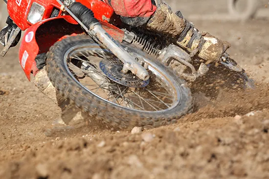 Motocross riders battling for position on a muddy race track during competitive racing