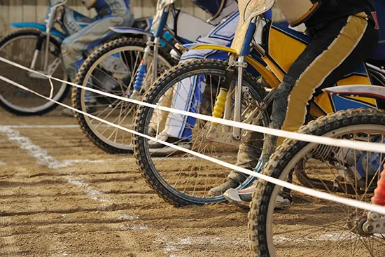 Speedway bikes lined up at the start of a race on a dirt track
